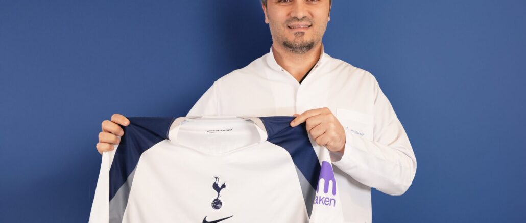 Bild zeigt, wie Dr. Abdulaziz Balwi ein Trikot des Premiere League Klubs Tottenham Hotspur in beiden Hände hält.