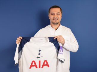 Bild zeigt, wie Dr. Abdulaziz Balwi ein Trikot des Premiere League Klubs Tottenham Hotspur in beiden Hände hält.