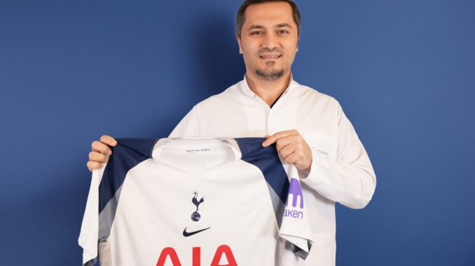 Bild zeigt, wie Dr. Abdulaziz Balwi ein Trikot des Premiere League Klubs Tottenham Hotspur in beiden Hände hält.
