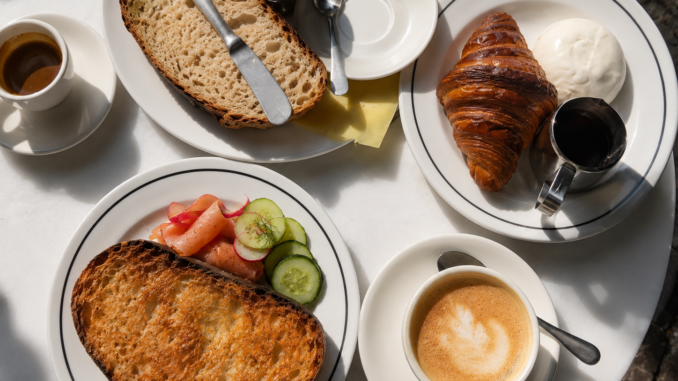 Frühstückstisch mit Croissant, Brot, Ei, Lachs, Gurken, Kaffee und weiteren Speisen als Beispiel für All you can eat in Berlin.