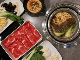 Hot Pot mit würziger Brühe, Nudeln, Pak Choi, dünn geschnittenem Rindfleisch, Pilzen und frischem Gemüse.