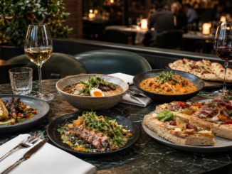 Gedeckter Restauranttisch mit Ramen, Curry, Focaccia, Gemüsegerichten und Wein in einem eleganten Wiener Lokal