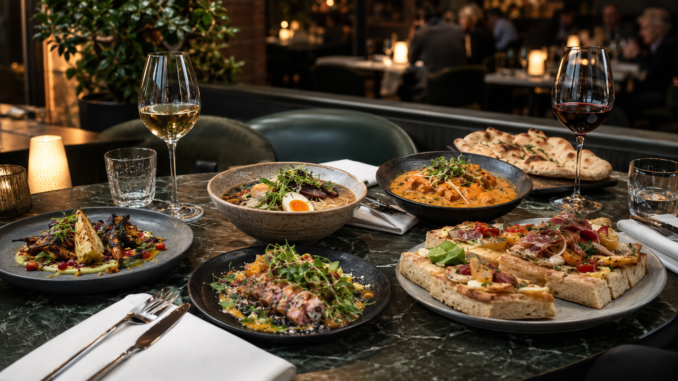 Gedeckter Restauranttisch mit Ramen, Curry, Focaccia, Gemüsegerichten und Wein in einem eleganten Wiener Lokal