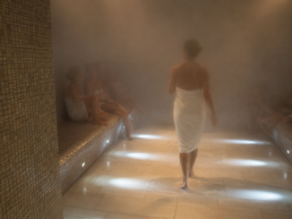 Dampfsauna in Wien mit mehreren Gästen, die in Handtücher gehüllt im warmen Dampfbad entspannen.