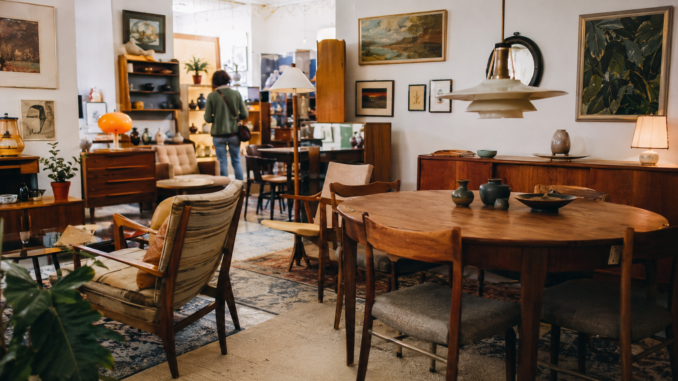 Innenansicht eines Wiener Vintage-Möbelgeschäfts mit Holztischen, Sesseln, Lampen, Sideboards und gerahmten Bildern
